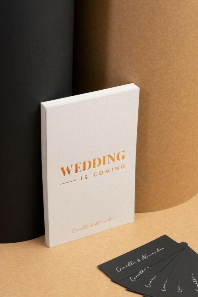 Wedding is comming – Save the date A6 en dorure à chaud Cuivre Saxon 6735 avec débossage sur Colorplan Pale Grey 540gr – Etiquette assortie impression blanche numérique du Sirio Black 290gr:m2