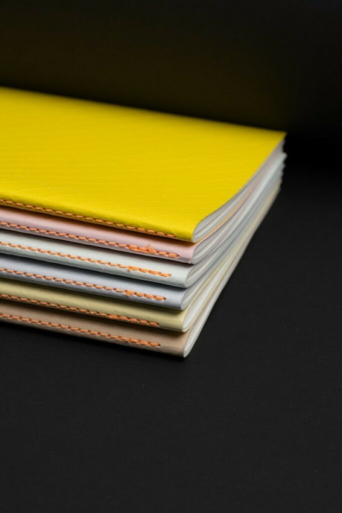 Collection de Carnets en couture singer Orange au pli et couverture embossée Colorplan 270gr/m2 – Stone, Sorbet Yellow, Azure Blue, Powder Green, Candy Pink, Factory Yellow