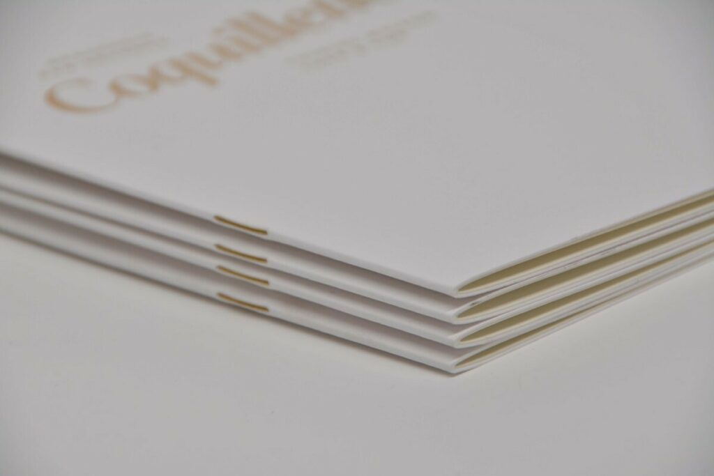 Brochure menu de restaurant raffiné avec deux agrafes dorées, et marquage à chaud satin gold 7122 sur papier texturé  Tintoretto Gesso 300g/m2 – intérieur Nature Touch Class 200gr/m2