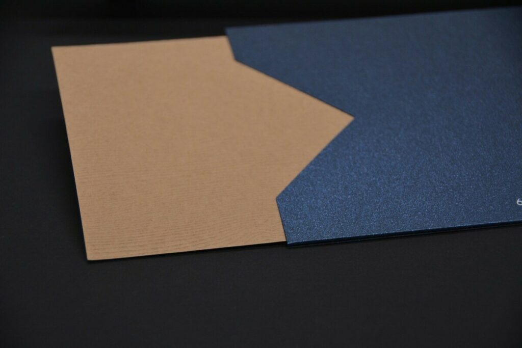 Pochette Menu pour restaurant gastronomique avec papier nacré et texture bois – Forme découpe sur mesure avec marquage à chaud blanc brillant – Sirio pearl shiny blue et Gmund savanna wood tindalo