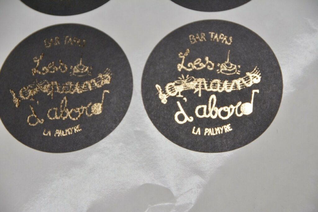 Stickers papier noir en dorure numérique OR et découpe laser ronde mi-chaire en planche