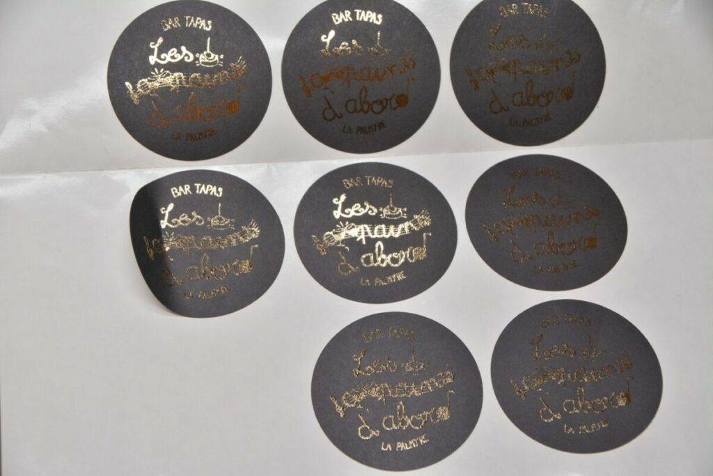 Stickers papier noir en dorure numérique OR et découpe laser ronde mi-chaire en planche