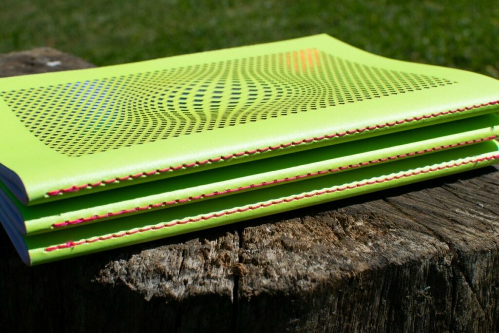 Collection de carnets de notes Illusonautes – Gmund action nuclear acid – découpe laser motifs holographiques laser – Reliure couture singer Rose Fluo – impression Pantone Rose fluo PMS 806
