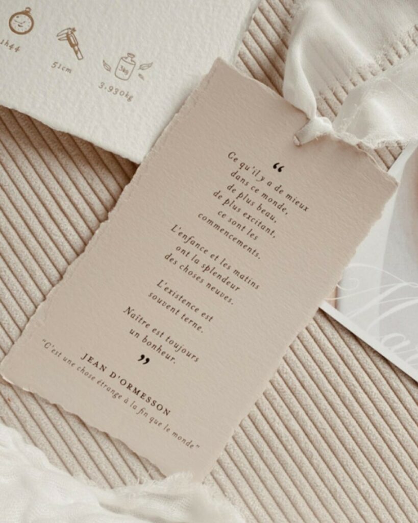 Faire-part de naissance bords frangés sur papier texturé Arches coton 400g – Marquage à chaud or mat et débossage pur – Ruban lin effiloché – cachet de cire blanc