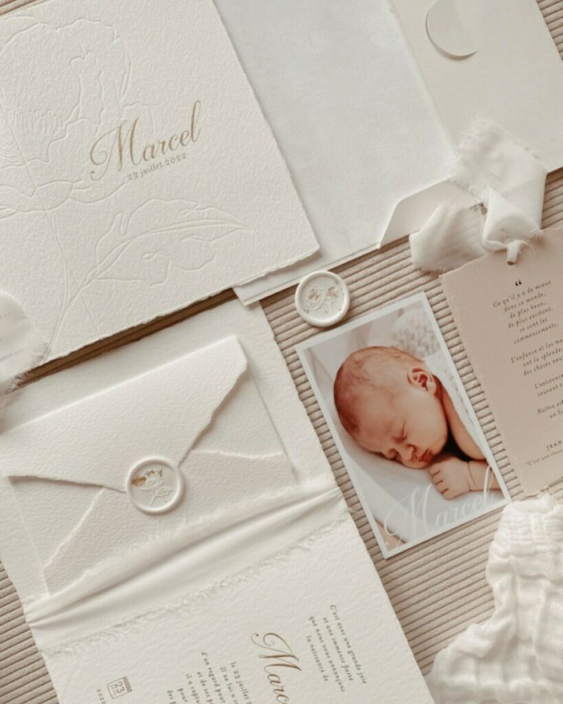 Faire-part de naissance bords frangés sur papier texturé Arches coton 400g – Marquage à chaud or mat et débossage pur – Ruban lin effiloché – cachet de cire blanc