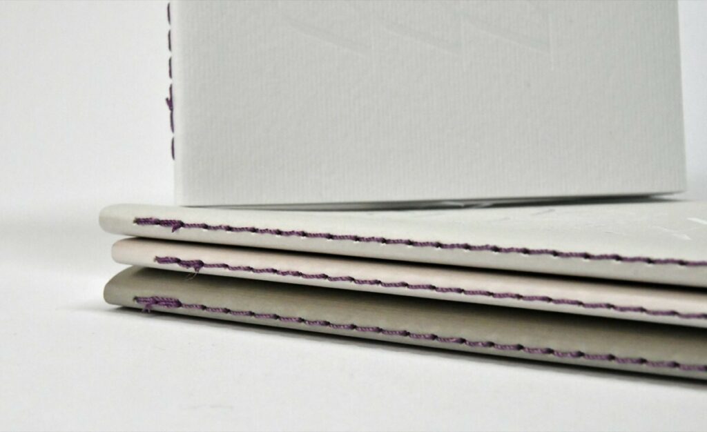 Carnets de notes L’Amour, Greige, nude et blanc naturel – Reliure en couture singer violette au pli – Dorure à chaud Blanc brillante – Papier texturé lignes Nettuno Pesca, Perla, Grigrio et Bianco Artico