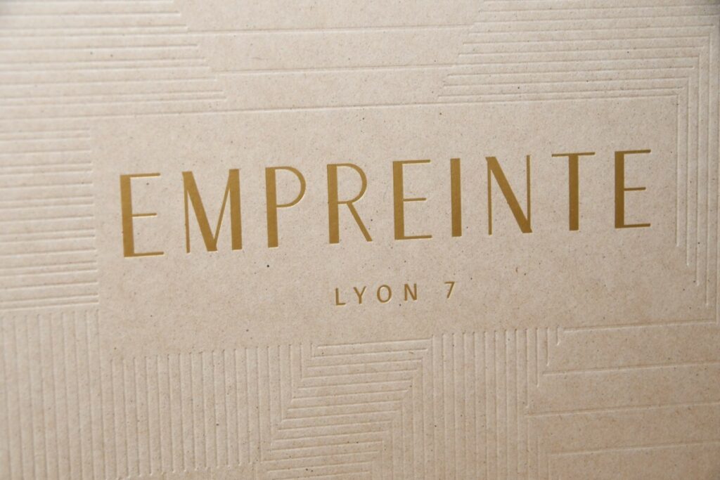 Book de présentation promoteur immobilier – Marquage à chaud or mat et débossage motifs en creux sans impression – Kraft recyclé cocoa shell 300g – Reliure en couture singer ton sur ton – 16 pages intérieur couché mat 300g
