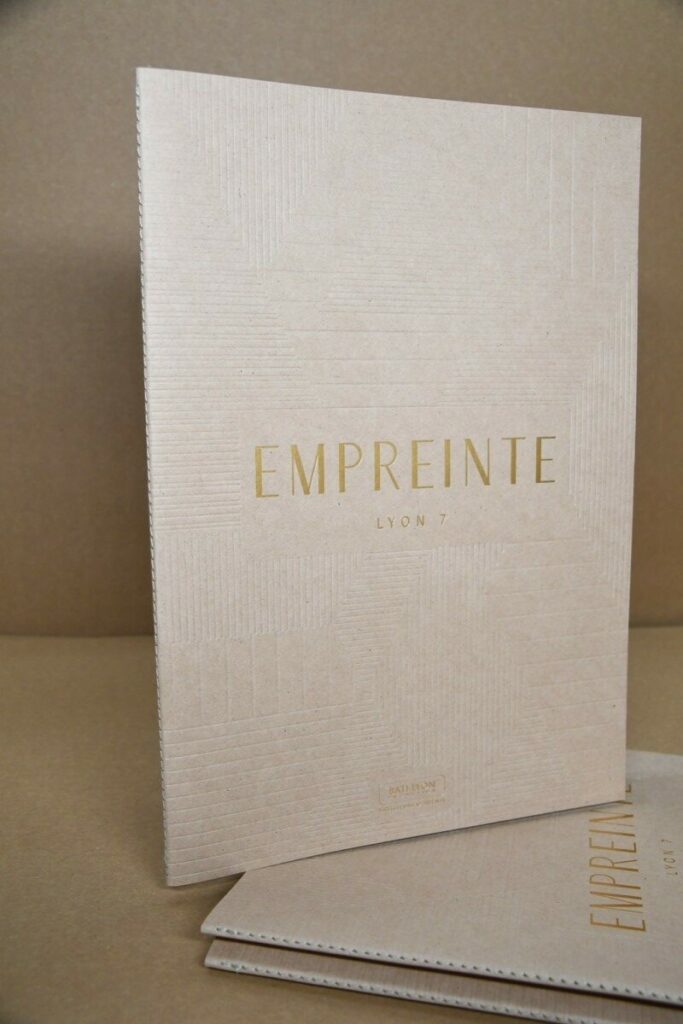 Book de présentation promoteur immobilier – Marquage à chaud or mat et débossage motifs en creux sans impression – Kraft recyclé cocoa shell 300g – Reliure en couture singer ton sur ton – 16 pages intérieur couché mat 300g