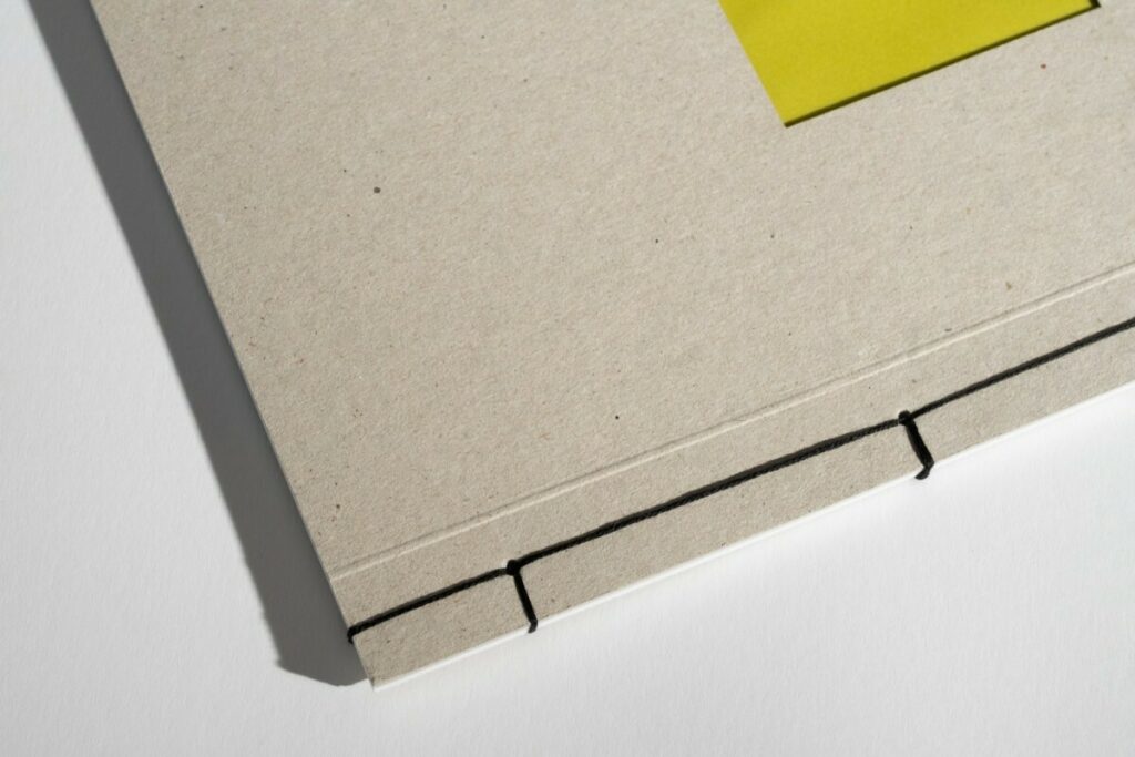 Porfolio pour photographe plasticienne avec reliure en couture Japonaise 4 points – Couverture en carton gris recyclé 350g avec découpe centrale