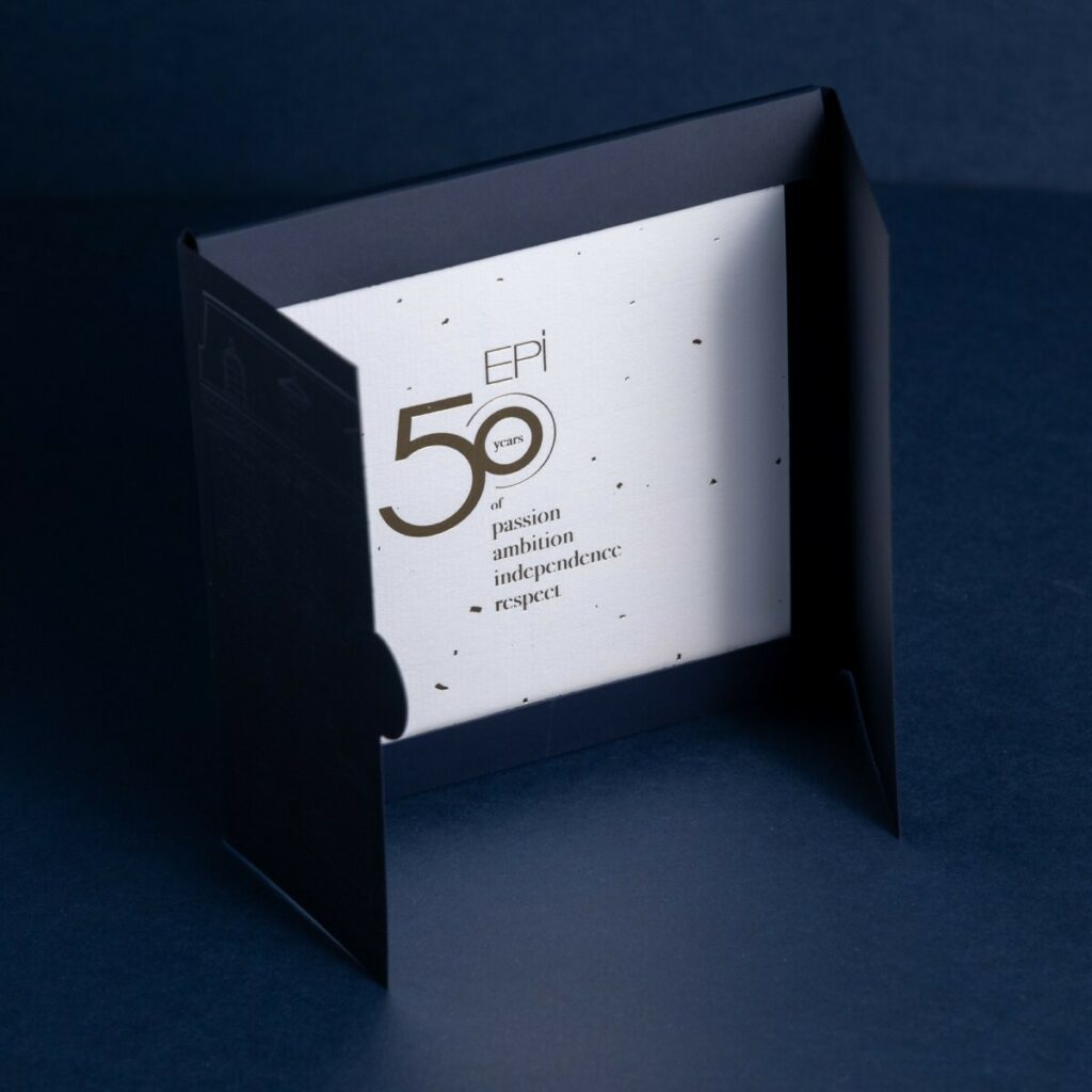 Carton d’invitation 50ans d’histoire avec une pochette a rabats et découpe sur mesure – Marquage à chaud transparent du château sur Sirio color dark blue – Invitation sur papier de création Vergé avec dorure à chaud or brilante
