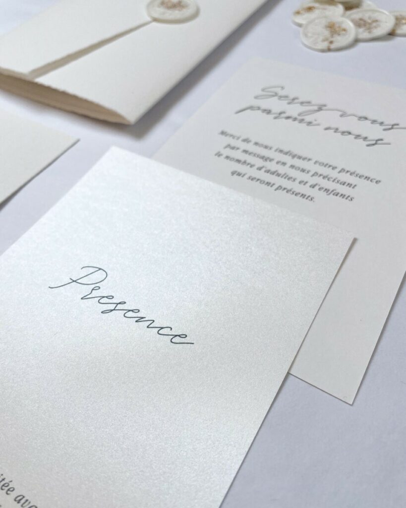 Faire-part de mariage pochette pockart, cachet de cire blanc inclusion feuille d’or et trombone doré – papier texturé Arches Expression – Papier irisé Sirio pearl
