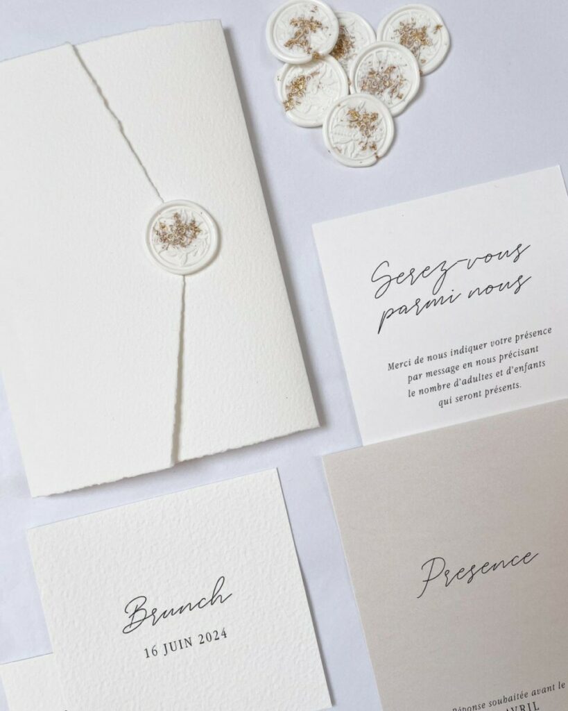 Faire-part de mariage pochette pockart, cachet de cire blanc inclusion feuille d’or et trombone doré – papier texturé Arches Expression – Papier irisé Sirio pearl