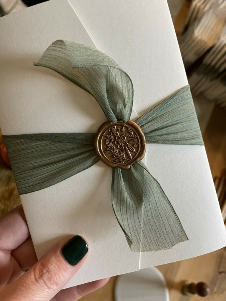 Faire-part de mariage floral pochette luxe avec ruban vert olive et cachet de cire bronze – Arches Expression texture 400g – découpe numérique ronde – old mill bianco 300g